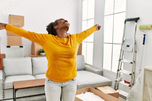 African american woman smiling confident standing with arms open at new home