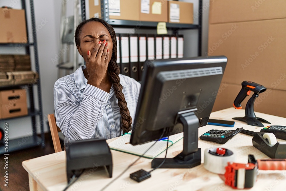 African woman working at small business ecommerce bored yawning tired covering mouth with hand. restless and sleepiness.