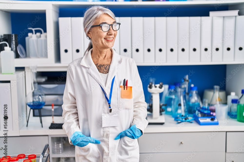 Middle age grey-haired woman scientist smiling confident standing at laboratory Middle age grey-haired woman scientist smiling confident standing at laboratory