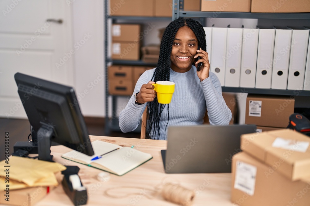 African american woman ecommerce business worker talking on smartphone drinking coffee at office African american woman ecommerce business worker talking on smartphone drinking coffee at office