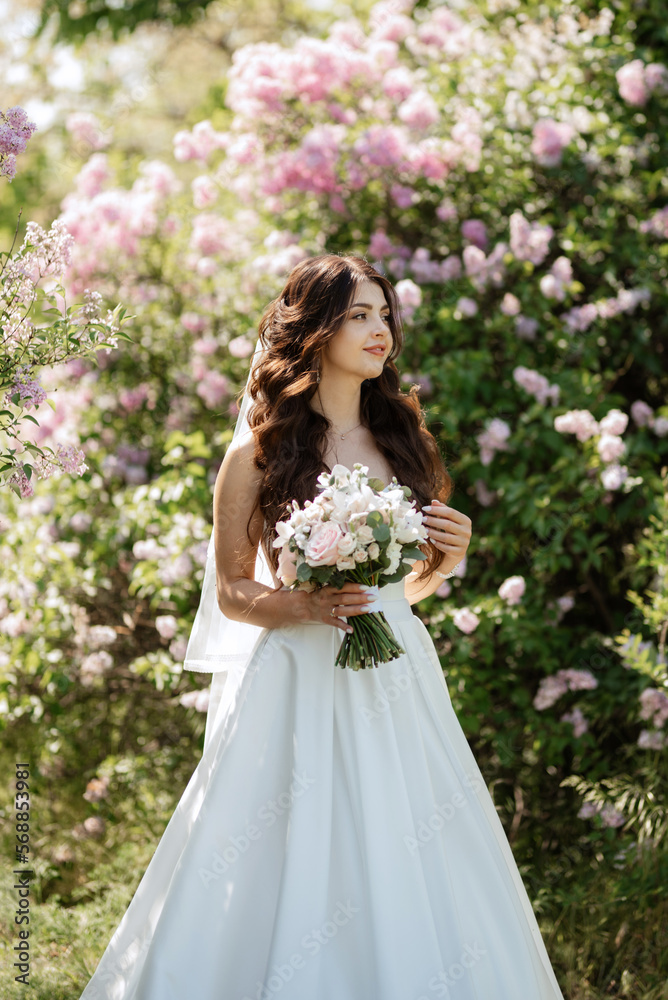 young girl bride in a white dress in a spring forest in lilac bushes