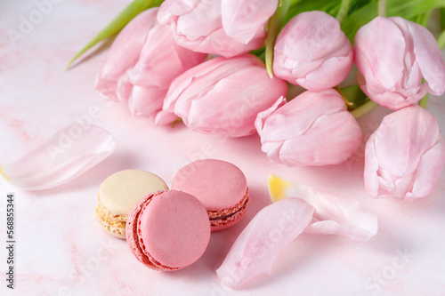 French sweet cookies macarons macaroons and bouquet of tulip flowers on marble background.