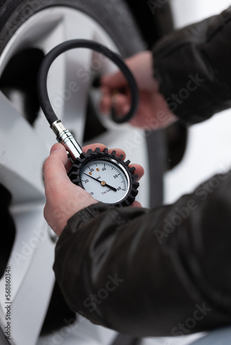 A man measures the pressure in the tire of his car tire