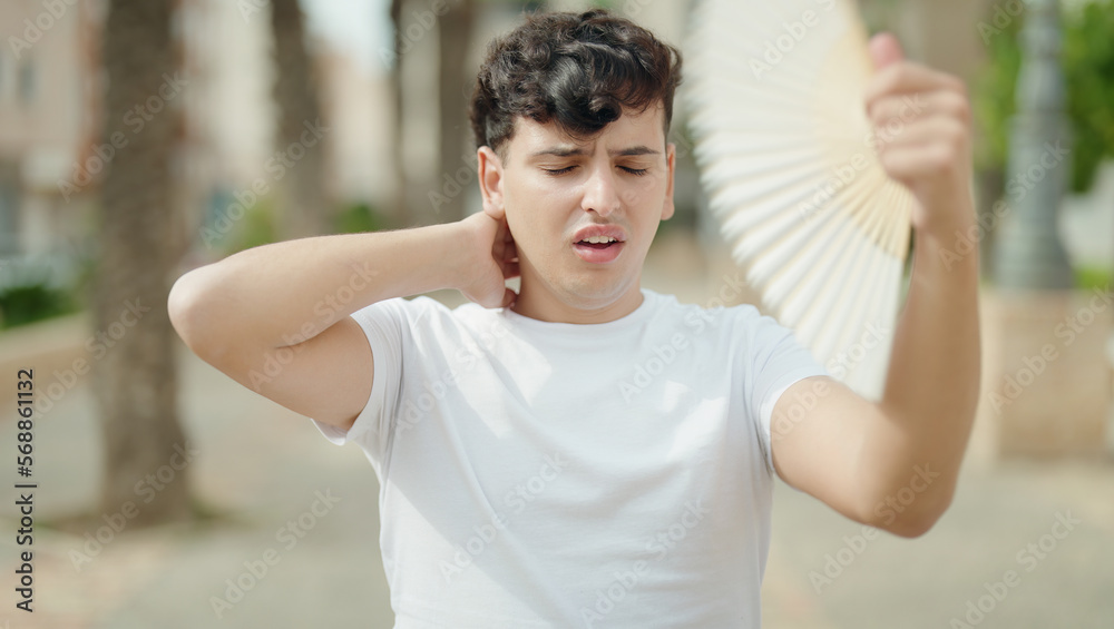Naklejka premium Non binary man using handfan suffering for hot at park