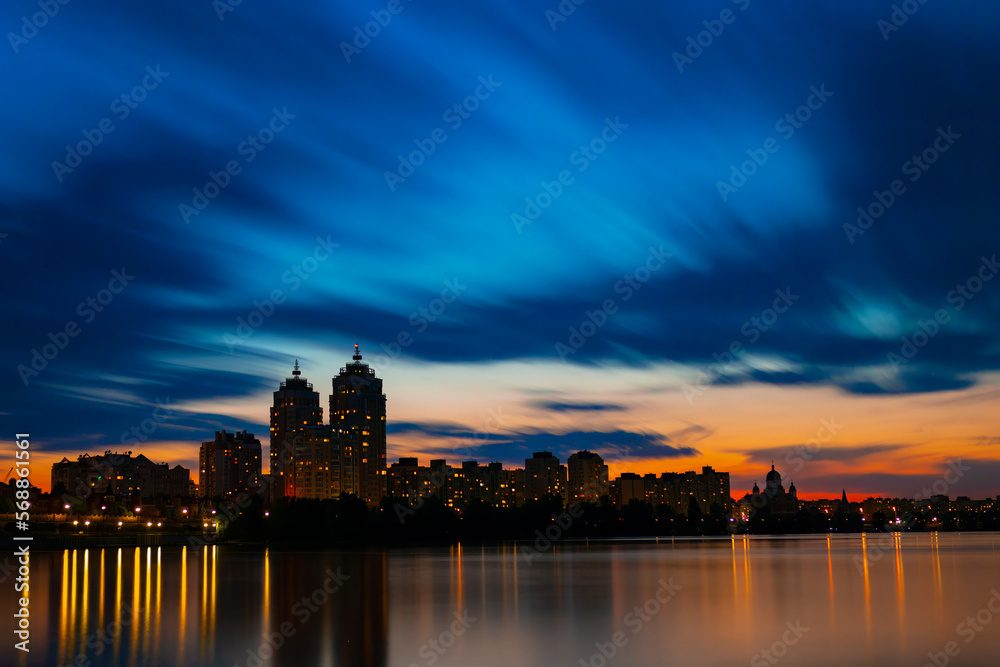Cityscape. The lights of the evening city. Reflections of houses in the river. Long exposure. Cityscape. The lights of the evening city. Reflections of houses in the river. Long exposure.