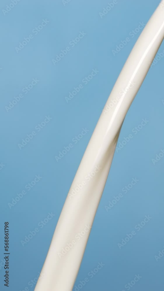 Vertical slow motion video, pouring farm fresh milk into jug on blue background, healthy milk drink concept. Vertical slow motion video, pouring farm fresh milk into jug on blue background, healthy milk drink concept.