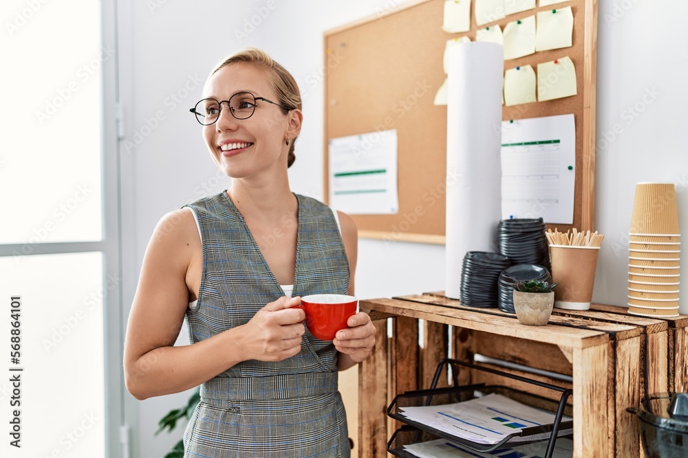Young caucasian woman smiling confident drinking coffee standing at office Young caucasian woman smiling confident drinking coffee standing at office