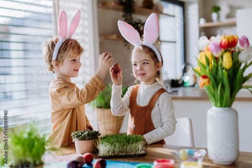 Little kids with bunny ears celebrating easter, playing easter game with egg.