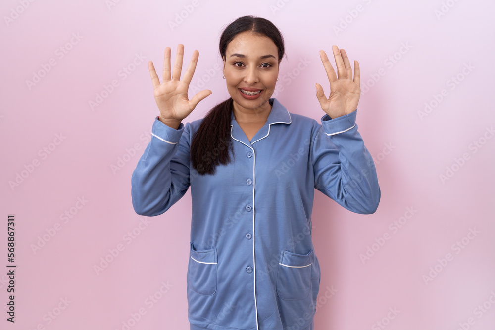 Young arab woman wearing blue pajama showing and pointing up with fingers number ten while smiling confident and happy. Young arab woman wearing blue pajama showing and pointing up with fingers number ten while smiling confident and happy.