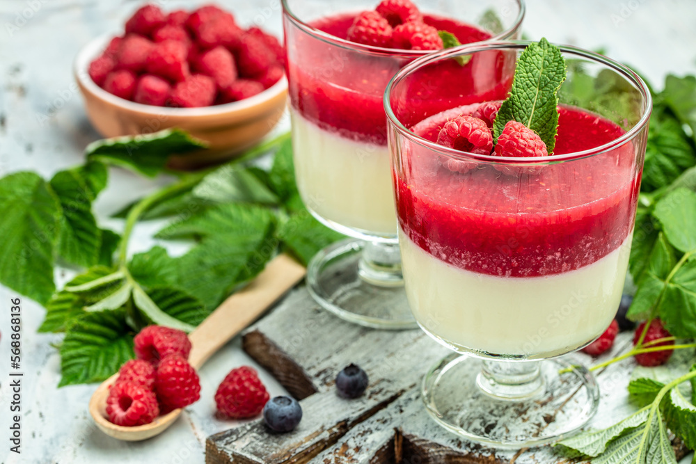 Raspberry Panna cotta with raspberry jelly on a light background. Berry dessert with cream sauce in small jars. place for text Raspberry Panna cotta with raspberry jelly on a light background. Berry dessert with cream sauce in small jars. place for text