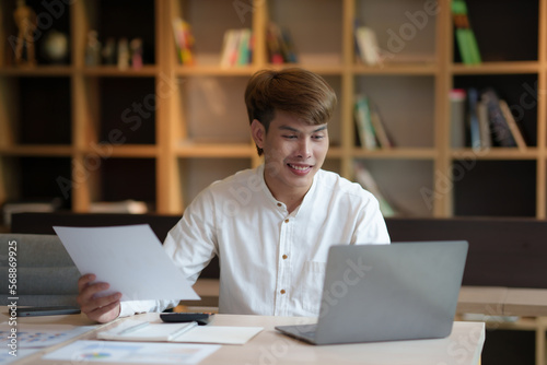 Young asian businessman sitting working with laptop computer in office