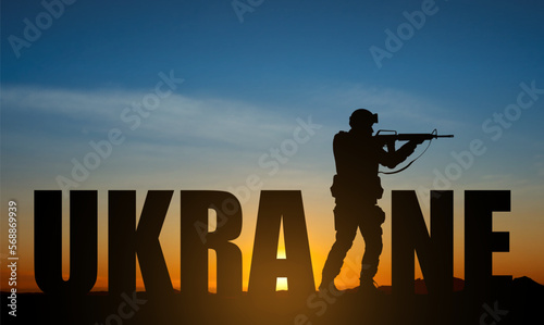 Stylized lettering - Ukraine with silhouette of soldier against sunset. EPS10 vector photo