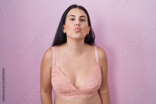 Young hispanic woman wearing pink bra looking at the camera blowing a kiss on air being lovely and sexy. love expression.