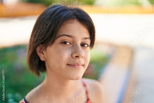 Adorable hispanic girl looking to the side with serious expression at park