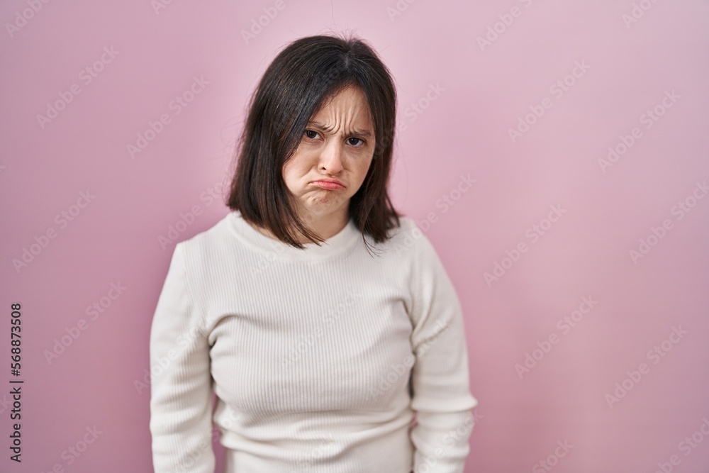Woman with down syndrome standing over pink background depressed and worry for distress, crying angry and afraid. sad expression. Woman with down syndrome standing over pink background depressed and worry for distress, crying angry and afraid. sad expression.