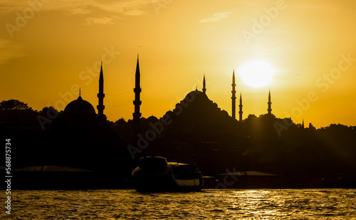 A ferry is seen on Bosphorus in Istanbul, Turkey. Minarets of mosques on the shores of Golden Horn are seen in the background during sunset.