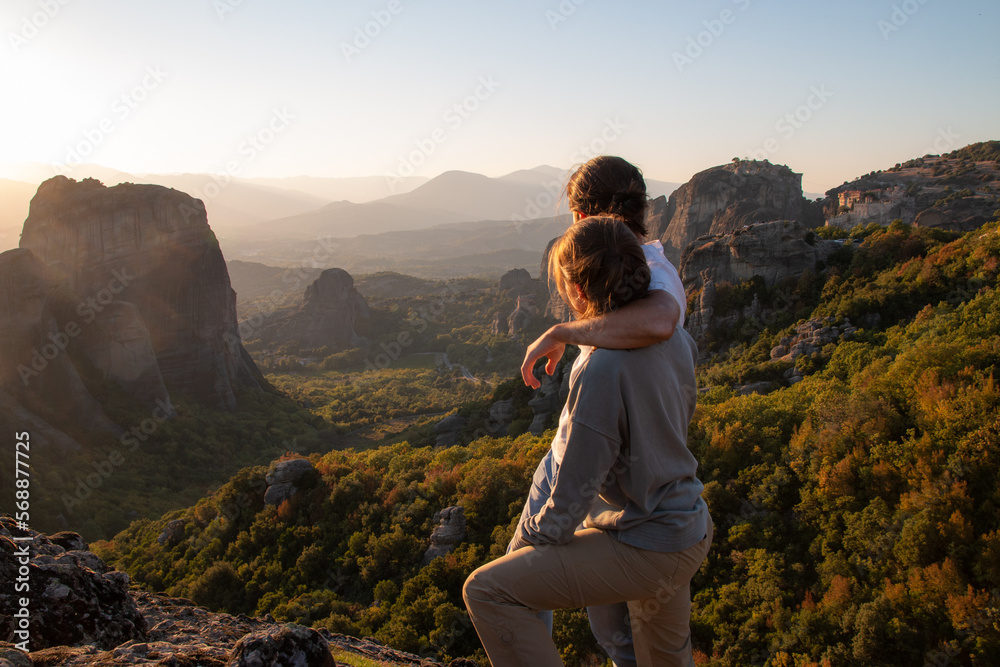 Couple from behind watching the sunset in Meteora in the golden hour