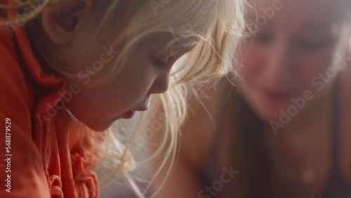 Close up view of baby girl learning how to read a book with mothers help, spending time together. Interested kid studying new things. Mom and daughter family time. High quality 4k footage