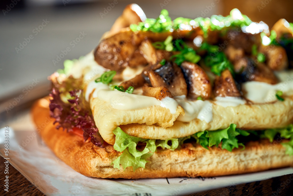 Breakfast sandwich with Omelette and mushrooms and white sauce. Concrete background. Hard light. Vegetarian food. Close up Breakfast sandwich with Omelette and mushrooms and white sauce. Concrete background. Hard light. Vegetarian food. Close up