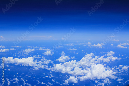 Cloudscape background. View from above, out of an airplane window. White clouds and blue sky with different shades.