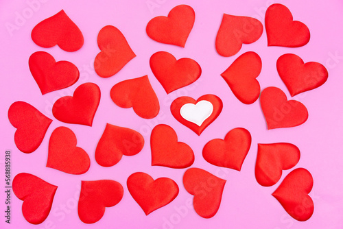 Bright red randomly scattered red hearts on a pink background. A declaration of love.