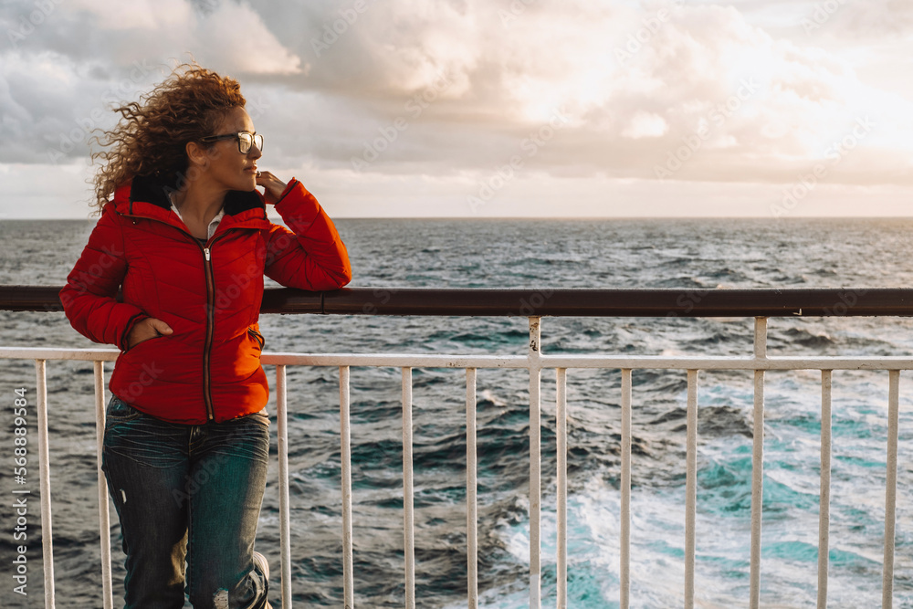 One woman traveling ocean with red jacket admiring water surface during sunlight sunset. Beautiful sky in background. Concept of female people travel on ferry cruise ship boat. Tourist enjoy transport