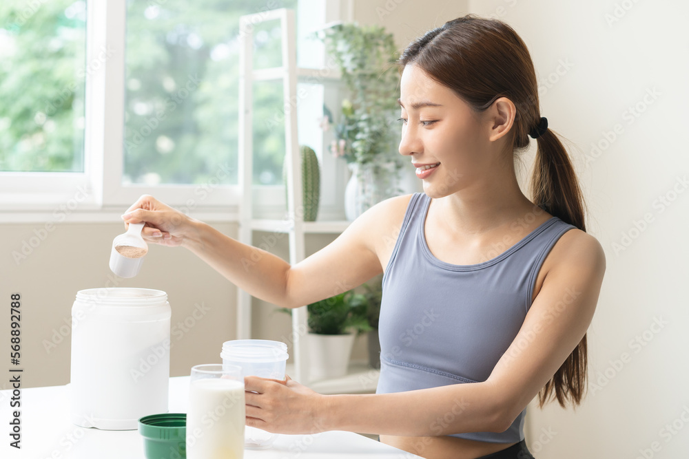 Diet meal replacement for weight loss, smile asian young woman, girl in sportswear, hand in holding scoop making protein shake, drink supplement for muscle after workout at home. Healthy body care. Diet meal replacement for weight loss, smile asian young woman, girl in sportswear, hand in holding scoop making protein shake, drink supplement for muscle after workout at home. Healthy body care.