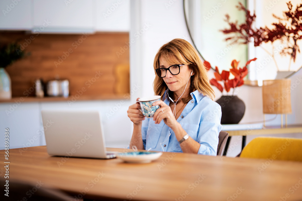 Attractive woman with earphones using her laptop at home Attractive woman with earphones using her laptop at home