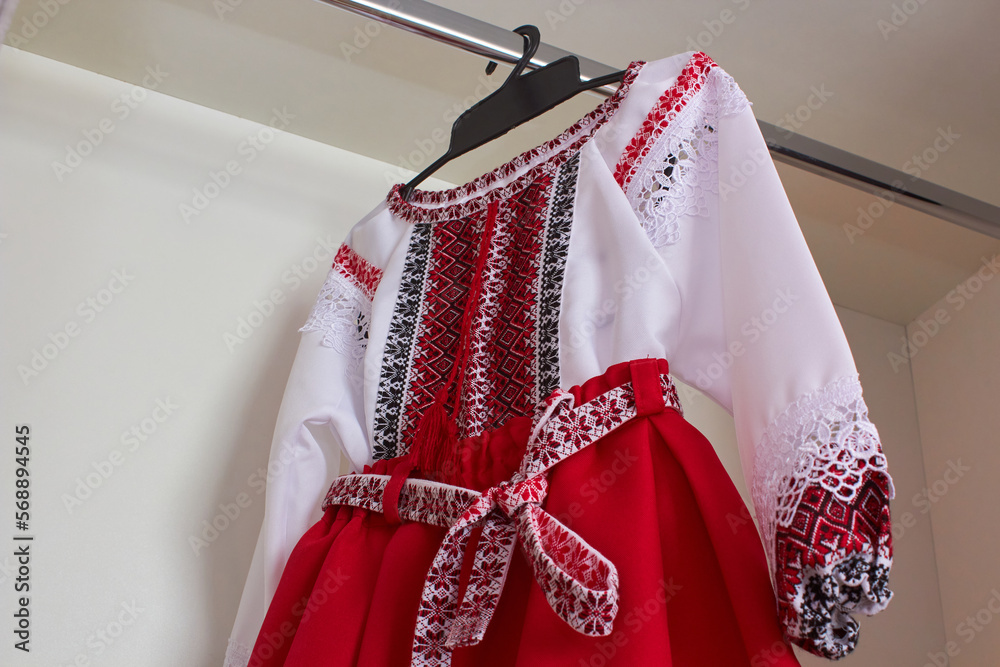 a red embroidered dress hangs on a hanger,blouse embroidered with red and black threads and skirt, Ukrainian embroidery