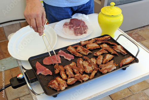 Cocinando lagartitos de cerdo ibérico a la brasa en plancha eléctrica. Solomillo ibérico para montaditos, exquisita carne ibérica para celebrar una reunión de amigos. photo
