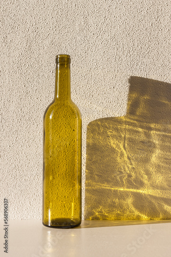 A bottle of wine in sunlight and its colored shadow. long shadow and refraction patterns. White background