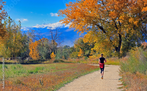 Female jogger on Boulder, Colorado's Teller Farm Trail in autumn, with the Continental Divide in the background © Jim Glab