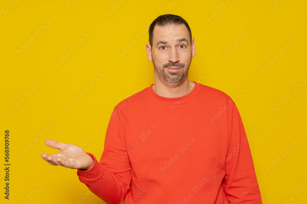 Bearded Hispanic man wearing turtleneck presenting an imaginary product between his hands, isolated on yellow background. Advertising concept. Bearded Hispanic man wearing turtleneck presenting an imaginary product between his hands, isolated on yellow background. Advertising concept.