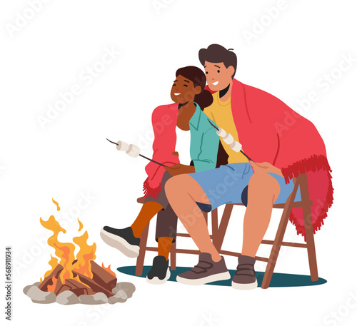 Young Man And Woman Couple Sitting At Campfire At Nighttime And Frying Marshmallow. Tourists In Summer Camp