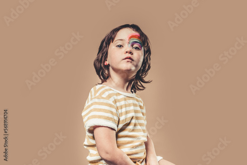 girl poses in studio with her face painted with rainbows © 23_stockphotography