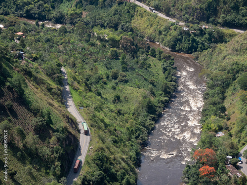 large general shot of vehicles driving along a road next to the river (Estrecho Magdalena, Isnos Huila Colombia) photo