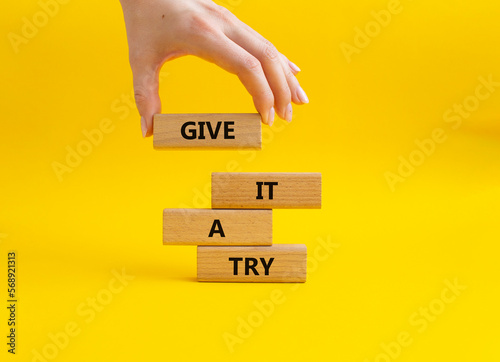 Give it a try symbol. Concept words Give it a try on wooden blocks. Beautiful yellow background. Businessman hand. Business and Give it a try concept. Copy space. photo