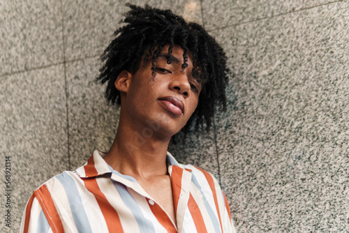 Foto joven latino con afro parado en la ciudad