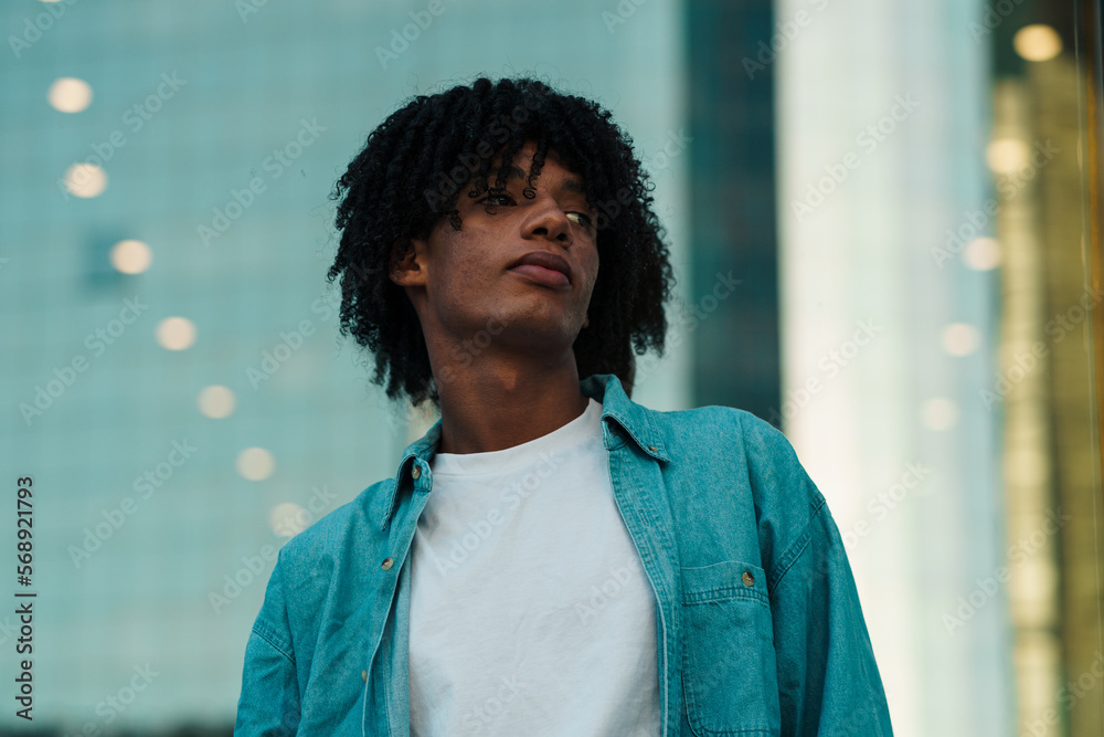 joven afroamericano posando y de espaldas en un vidrio en la ciudad ...