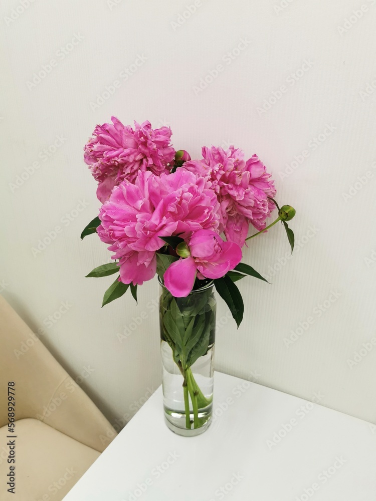 Obraz premium Bouquet of peony in a glass vase on the table.