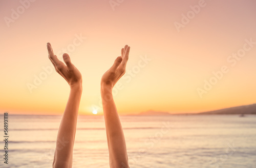 Thankfulness, and worship concept. Hands reaching out to sunset sky, warm sunshine in the palm of hands. 