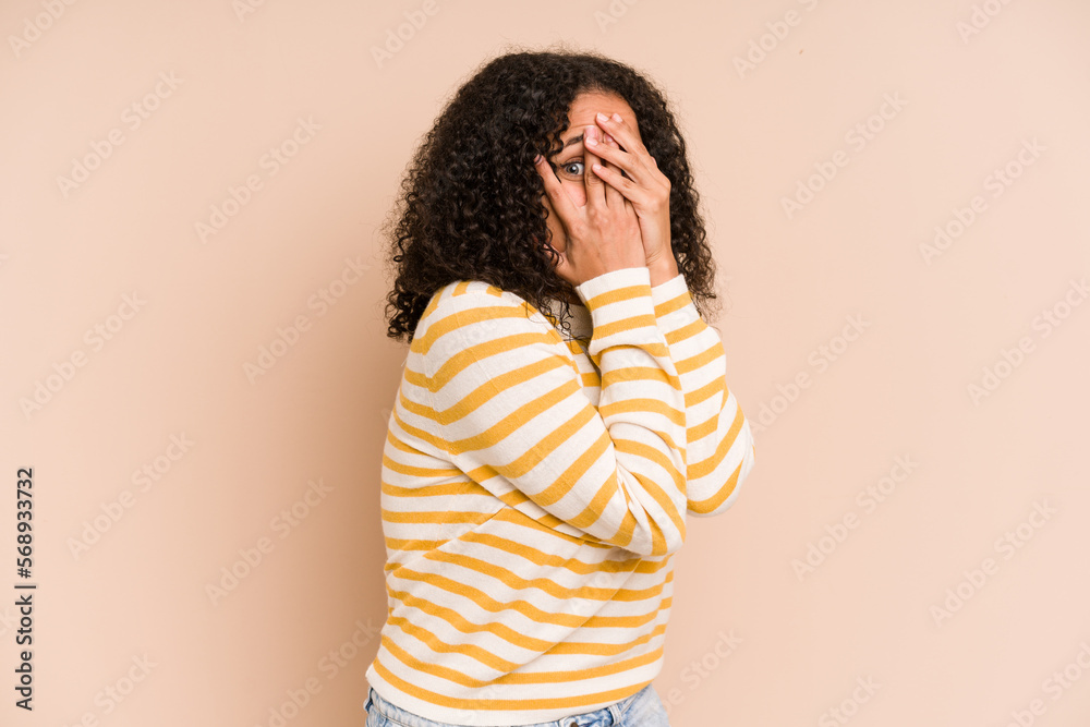 Young african american curly woman isolated blink through fingers frightened and nervous. Young african american curly woman isolated blink through fingers frightened and nervous.