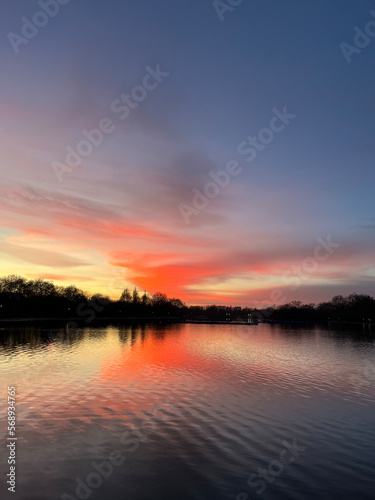 Fototapeta Naklejka Na Ścianę i Meble -  Pink and deep purple coloured sky and tranquil light at the sunset. The lights are mesmerising as the reflections of trees and birds are seen in the lake. Relaxation vibes. The atmosphere of calmness 