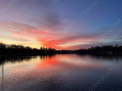 Pink and deep purple coloured sky and tranquil light at the sunset. The lights are mesmerising as the reflections of trees and birds are seen in the lake. Relaxation vibes. The atmosphere of calmness 