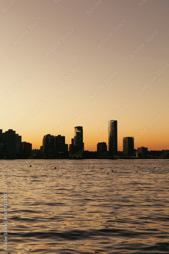 Hudson river and buildings on riverbank during sunset in New York City.
