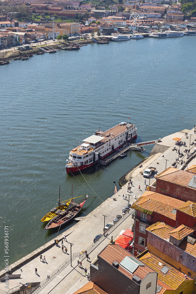 top view of a cruise liner and vintage boats for transporting port wine on the Douro river in the portuguese city of Porto