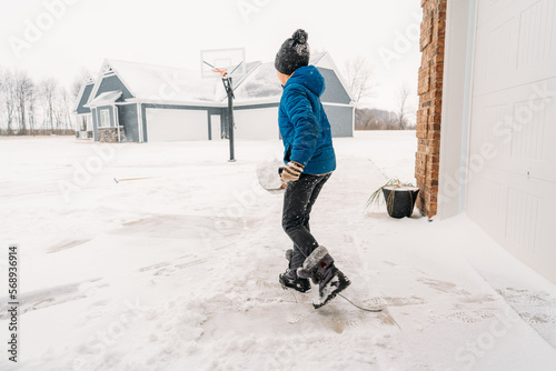A boy carrying a shovelful of snow. 