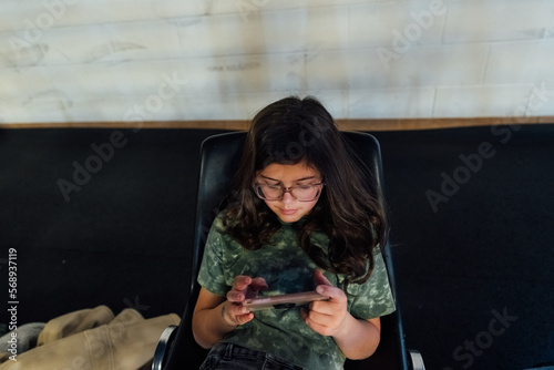Top-down view of a girl playing a video game on her phone. 