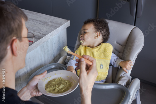 baby rejecting to eat food in high chair photo