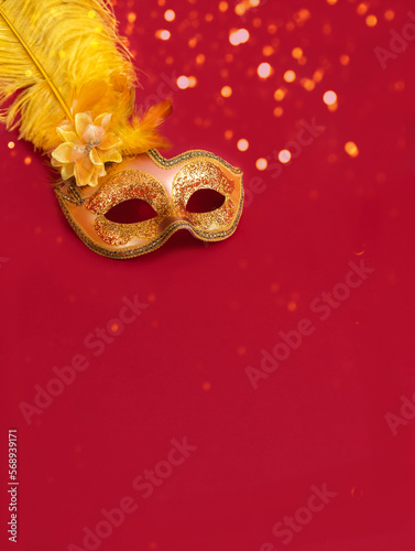 Golden Carnival mask against background in shades of red with sparkles. Mardi Gras concept or New Years decoration. Concept festive background or design. Close-up
